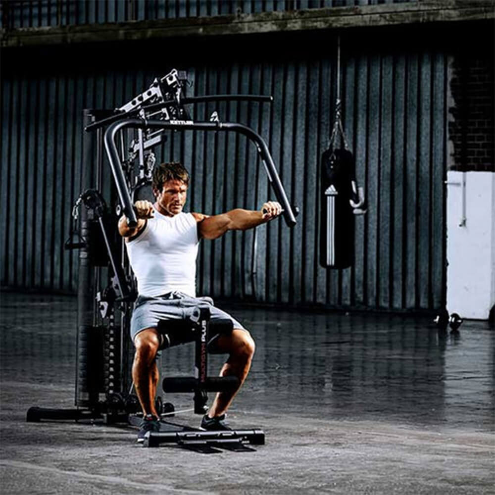 Vyras sportuojantis su Kettler jėgos treniruokliu sporto salėje