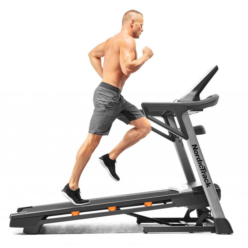 Pakeltas bėgimo takelis nordictrack, kuriuo naudojasi raumeningas vyras